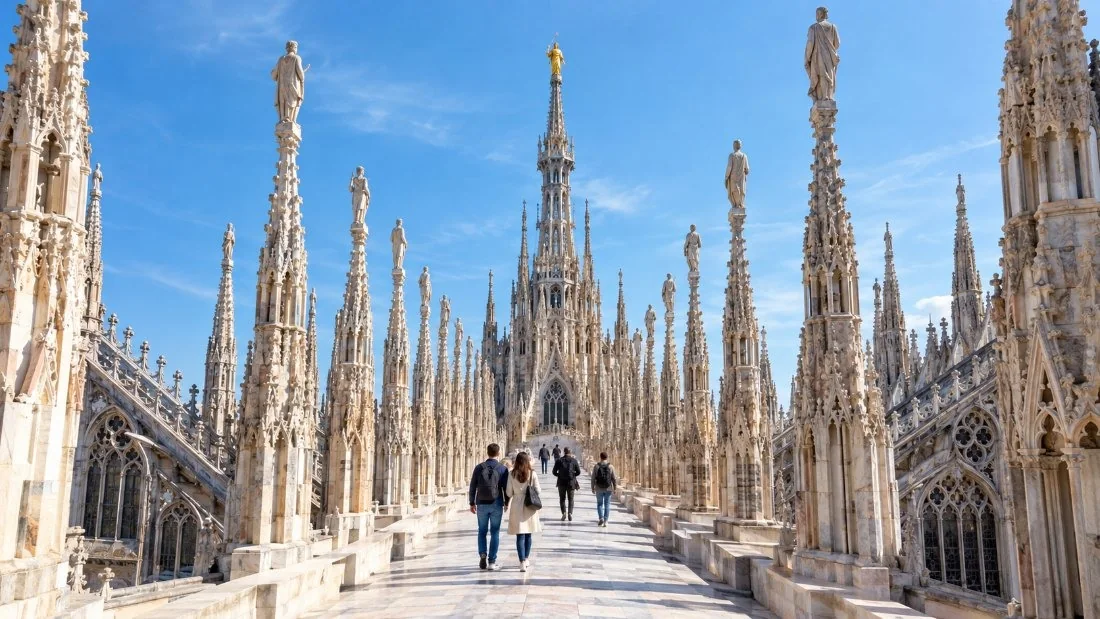 Visitors walking along the rooftop terraces of the Duomo di Milano between rows of carved marble spires and statues